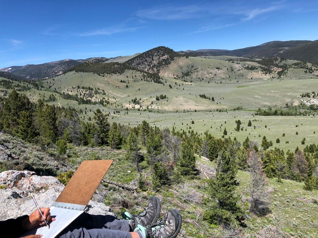 Sketching a cross-section on a clipboard above a green Montana valley